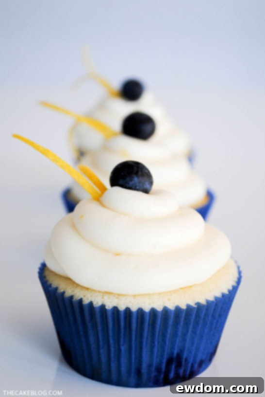 Close-up of a Lemon Blueberry Cupcake showing the fluffy cake, embedded blueberries, and smooth lemon cream cheese frosting.