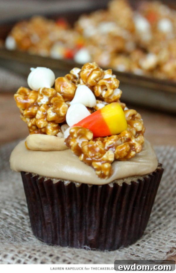 Sweet & Salty Popcorn Cupcakes 6 A tray of beautifully frosted Caramel Corn Cupcakes, adorned with a generous topping of homemade caramel corn, candy corn, and cashews