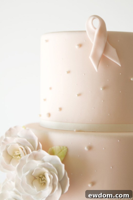 Close-up detail of The Pastry Studio's Awareness Cake, featuring the subtle pink ribbon and graceful design, shared on TheCakeBlog.com.