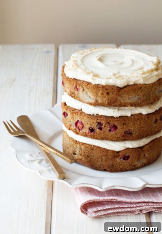 Beautifully frosted Pear & Cranberry Cake, ready for serving at a holiday celebration. By Tessa Huff for TheCakeBlog.com