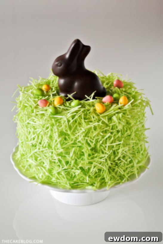 Arrangement of edible grass, chocolate bunny, and candy eggs on an Easter cake