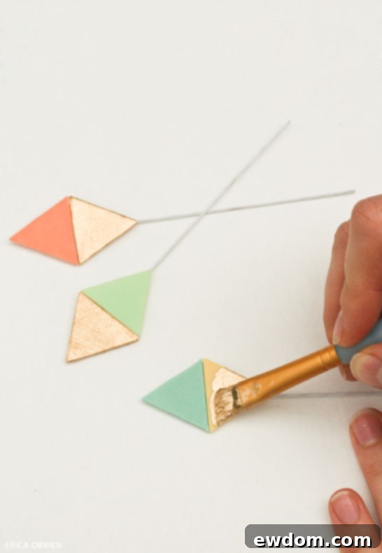Edible gold-painted fondant triangles drying, showcasing the pastel yellow base color technique