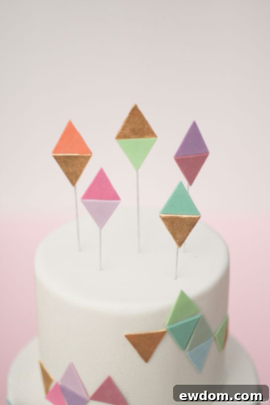 Assortment of handmade geometric cake toppers, including gold-painted and pastel fondant pieces