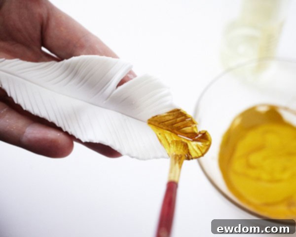 Painting gold and coral stripes onto dried fondant feathers