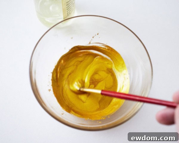 Mixing gold luster dust with clear extract to create edible metallic paint