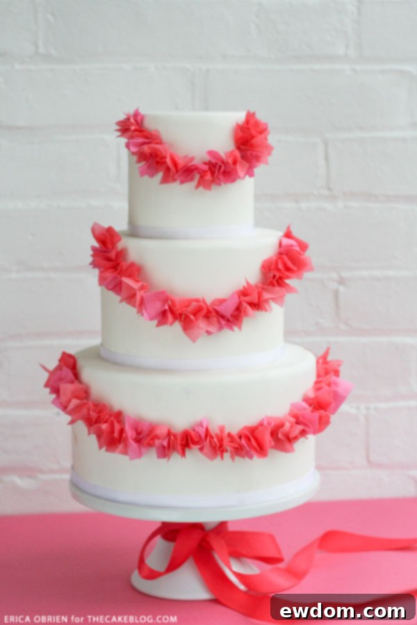Erica O'Brien's Paper Garland Cake beautifully displayed on a white porcelain stand with a magenta ribbon accent