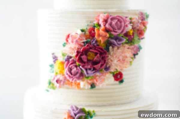 Close-up of textured buttercream on a wedding cake, accented with vibrant piped flowers, by Erica OBrien Cake Design