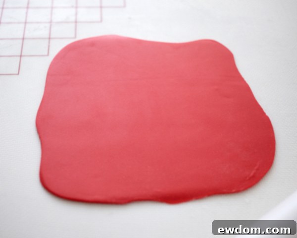 Valentines Candy Heart Surprise Cake 21 Rolling out a sheet of vibrant red fondant for cake covering