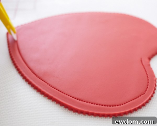 Valentines Candy Heart Surprise Cake 28 Using a stitching wheel to create a delicate inner border on the red fondant heart