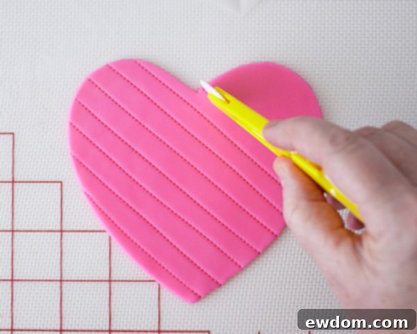 Valentines Candy Heart Surprise Cake 30 Cutting a hot pink fondant heart and creating angled stitching lines with a tool