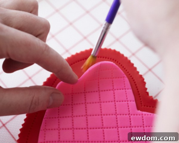 Valentines Candy Heart Surprise Cake 32 Attaching the quilted hot pink fondant heart to the top of the red cake box base