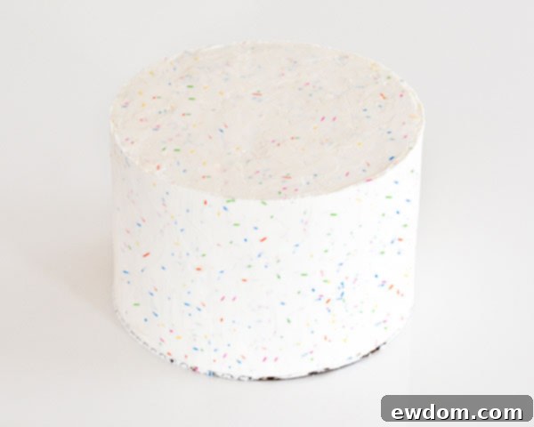 Smoothing the sprinkle buttercream on the cake's surface, ensuring a flat top for the edible image on this Graduation Party Dessert.