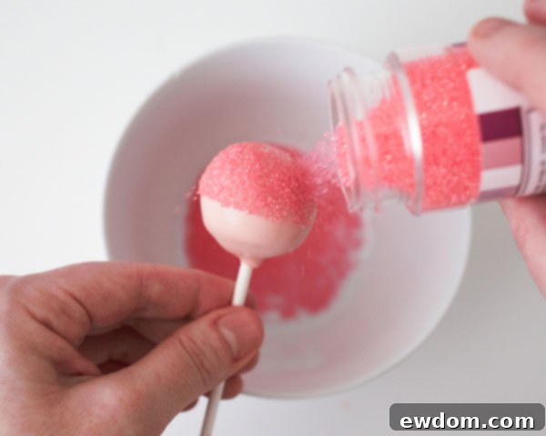 Sprinkle baby rattle cake pops with pink sanding sugar.