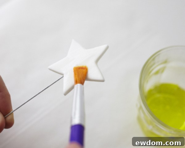 Applying glittery disco dust to a gumpaste star cake topper with egg white | by Cakegirls for TheCakeBlog.com