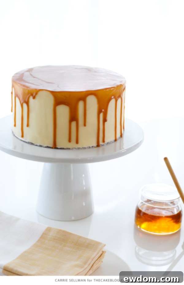 Close-up of a slice of Honey Butter Cake, showing the moist honey cake layers, thick honey cream cheese frosting, and the glossy butterscotch glaze.