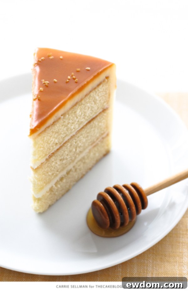 A stunning side view of the Honey Butter Cake, displaying the beautiful layers, frosting, and the glossy drip of honey butterscotch glaze.