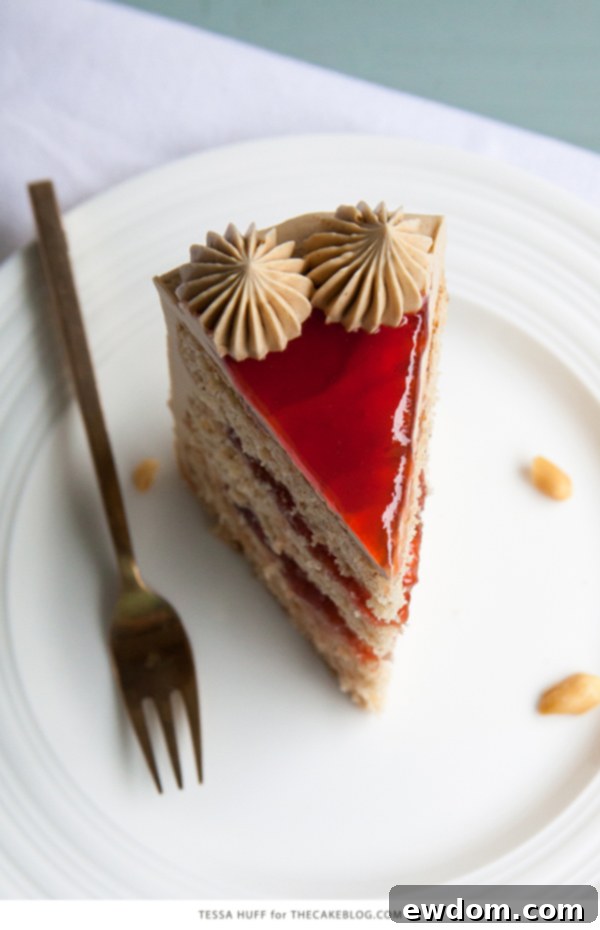 Slice of Peanut Butter & Jelly Cake showing layers of peanut butter cake, strawberry jam, and brown sugar peanut butter frosting