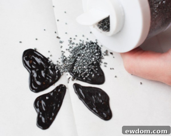 Sprinkling silver sanding sugar over wet black candy melt butterfly wings