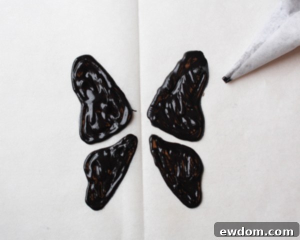 Filling in the piped butterfly wing outlines with black candy melts