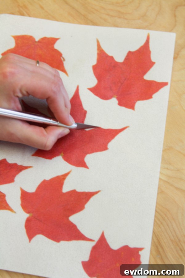 Detailed close-up of translucent wafer paper leaves for a fall cake, demonstrating the stem attachment technique