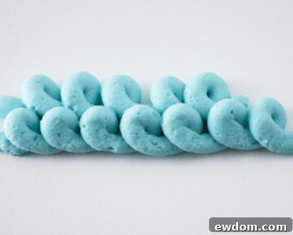 Another view of piping blue buttercream loops on the Winter Hat Cake