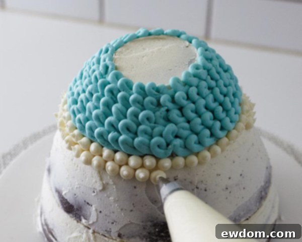 Piping white buttercream dots to create a contrast band on the hat cake