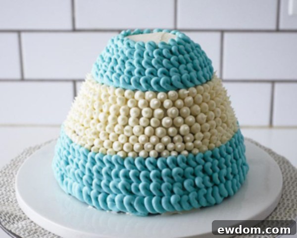 Finishing the knitted texture by piping blue loops to the bottom of the cake