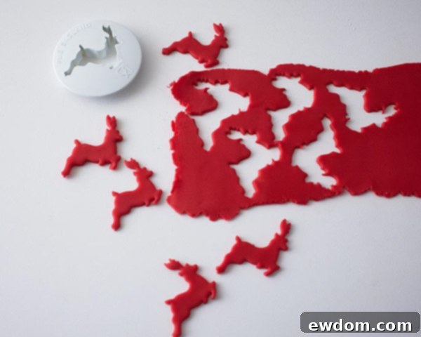 Rolling red fondant and cutting out festive reindeer shapes