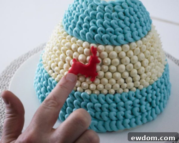 Gently attaching fondant reindeer onto the white band of the Winter Hat Cake