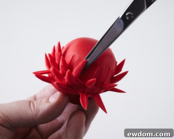 Cutting the fondant ball with scissors to create a fluffy pom-pom texture