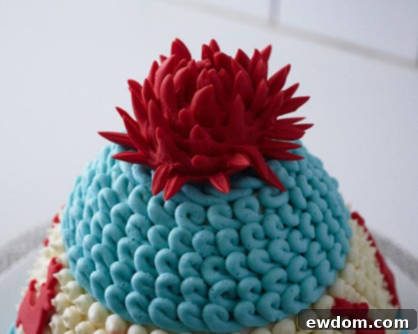 Placing the finished fondant pom-pom on top of the knitted hat cake