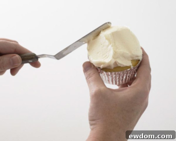 Cupcakes being piled high with white buttercream icing to form snow-like hills for the ski scene.