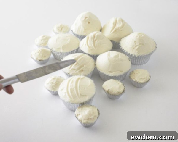 A butter knife creating grooves in the buttercream icing to form ski trails on the cupcake hills.