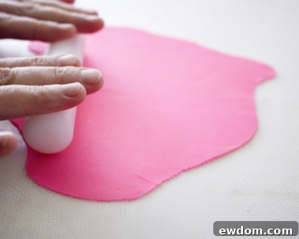 Blossom Cake Pops 11 Rolling out pink fondant thinly on a powdered sugar-dusted surface.