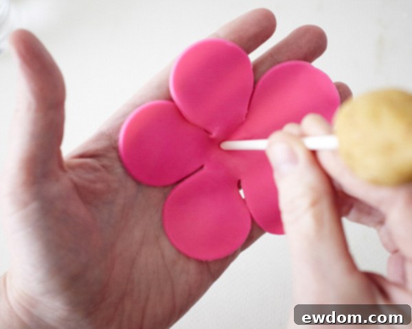 Blossom Cake Pops 13 Placing fondant flower in palm and poking chilled cake pop through its center.