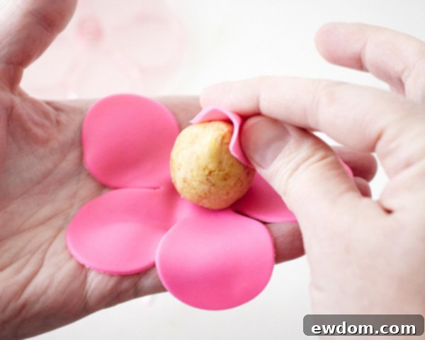 Blossom Cake Pops 14 Lifting and wrapping fondant petal #1 around the cake pop teardrop to form the rosebud.