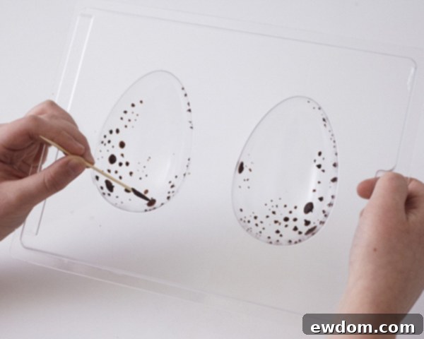 Step 3: Speckled chocolate dots inside the egg mold, chilling to set.