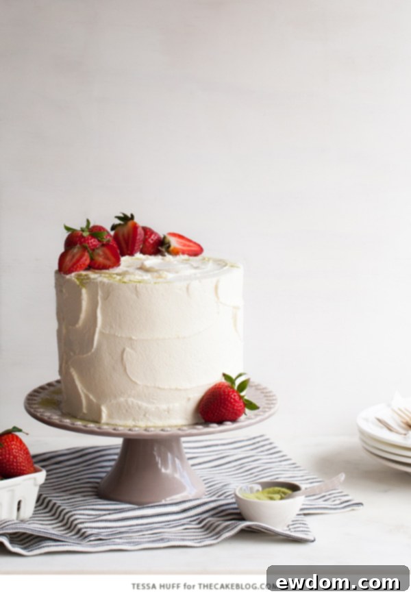 Strawberry Matcha Delight 4 A slice of Matcha Strawberry Cake revealing distinct layers of green matcha genoise, strawberry jam, and creamy white frosting.
