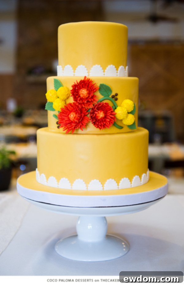 Warm earthy yellow cake adorned with stylized sugar spider mums and billy balls by Coco Paloma Desserts, perfect for a rustic or botanical celebration.