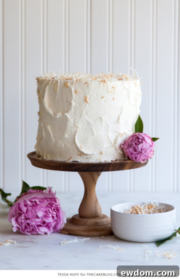 Tropical Coconut Tres Leches Cake 3 Close-up of a slice of Coconut Tres Leches Cake, showcasing the moist layers soaked in milk and topped with whipped cream and toasted coconut, by Tessa Huff