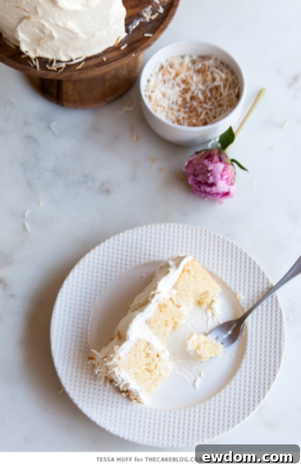 Tropical Coconut Tres Leches Cake 6 A beautifully frosted Coconut Tres Leches Layer Cake, showcasing the texture of the whipped cream and toasted coconut, ready for slicing, by Tessa Huff