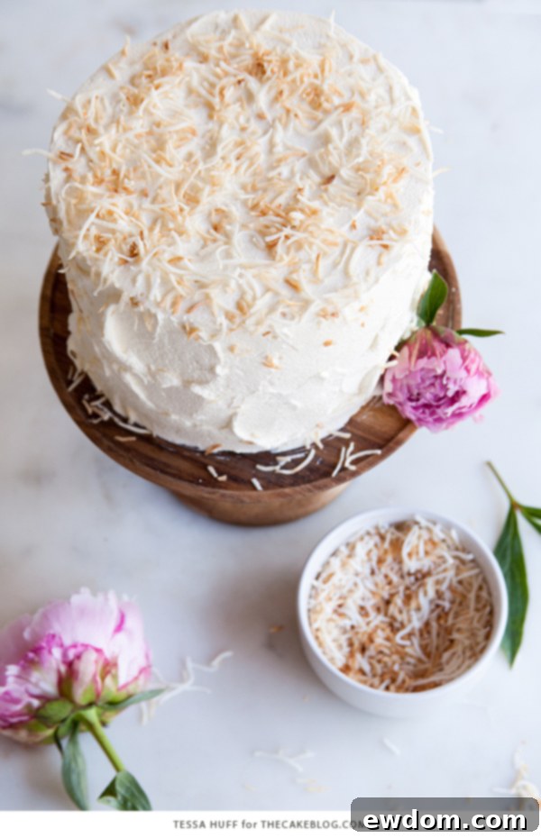 Tropical Coconut Tres Leches Cake 7 A generous slice of Coconut Tres Leches Cake on a plate, revealing its moist layers, creamy filling, and toasted coconut topping, by Tessa Huff