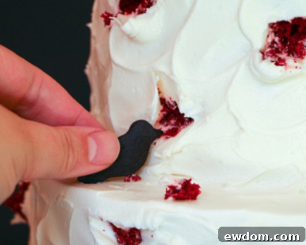 Arranging black bird cookies to look like they are attacking the cake