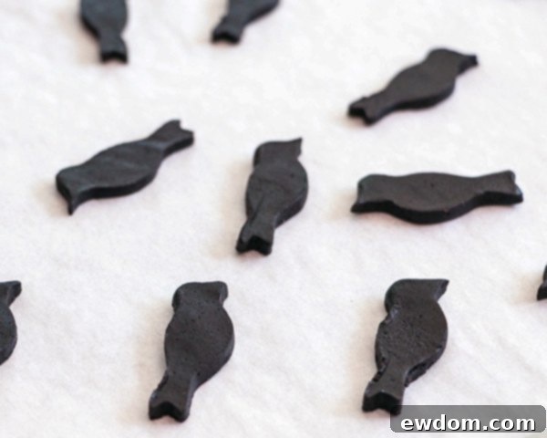 Arranging black bird cookies on parchment paper before baking