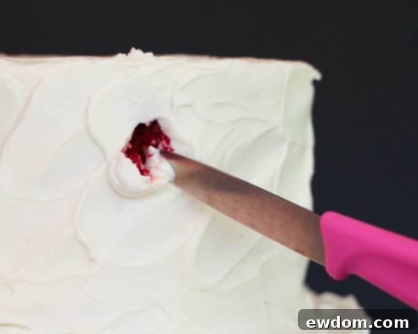 Using a small knife to gouge holes in the frosted red velvet cake