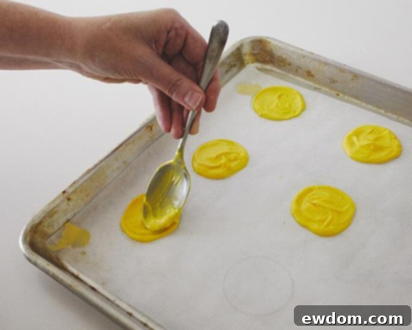 Spreading Melted Yellow Candy Coating into Circles on Parchment Paper