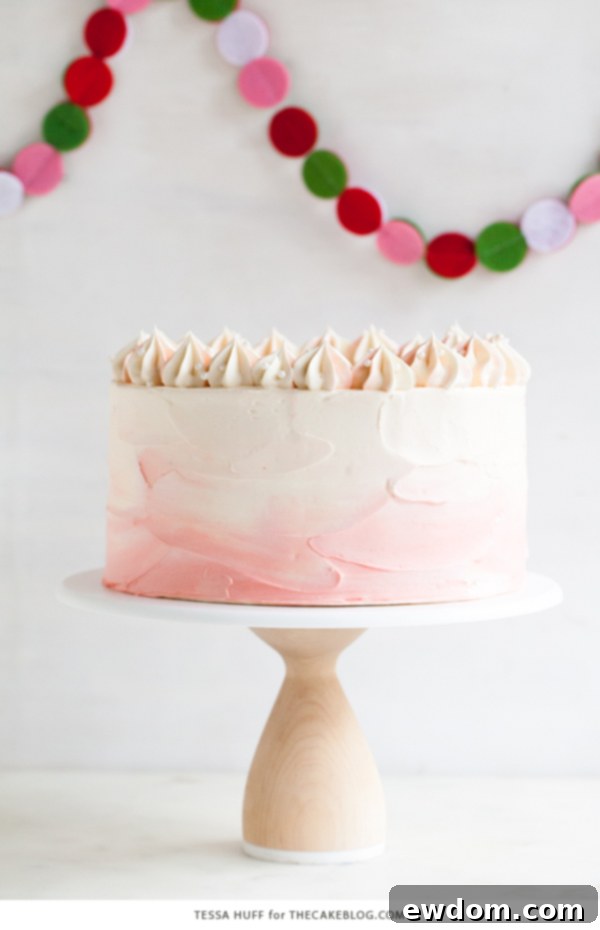 Overhead view of a perfectly frosted Peppermint Red Velvet Cake with decorative pink swirls and sparkling sugar