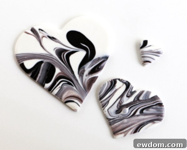 A collection of freshly cut marbled chocolate hearts displayed on wax paper, ready for further decoration or immediate use.