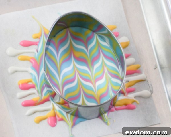 Elegant Swirl Easter Chocolates 17 Pressing an egg-shaped cookie cutter into freshly marbled chocolate to create the desired shape before it hardens.