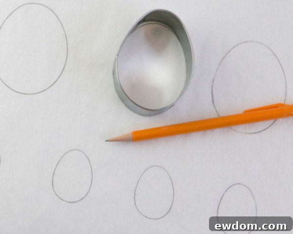 Elegant Swirl Easter Chocolates 8 Tracing egg cookie cutter outlines onto parchment paper using a pencil to create templates for chocolate marbling.